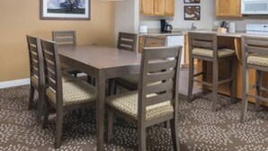 Un coin repas avec une table et des chaises, des meubles en bois, un four à micro-ondes et un tableau encadré au mur.