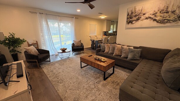 A modern living room with a sofa, armchairs, a coffee table, and a dining area with a table and chairs. - Updated Westbury Getaway Gem - 3 bedroom oasis (Houston)