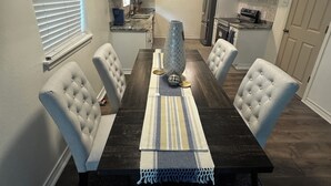 A dining room with a dark wooden table, four upholstered chairs, a striped runner, and a decorative vase. - Updated Westbury Getaway Gem - 3 bedroom oasis (Houston)