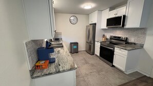 A modern kitchen with white cabinets, a stainless steel refrigerator, a microwave, and a built-in oven. - Updated Westbury Getaway Gem - 3 bedroom oasis (Houston)