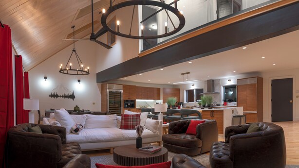 Amplia sala de estar con techo alto, muebles modernos y una cocina al fondo.