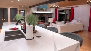 Una sala de estar moderna con una isla de mármol, chimenea y un ventanal con cortinas rojas.
