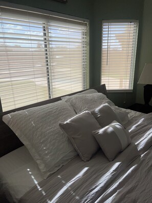 A bed with white linens and pillows, a nightstand, and a lamp.