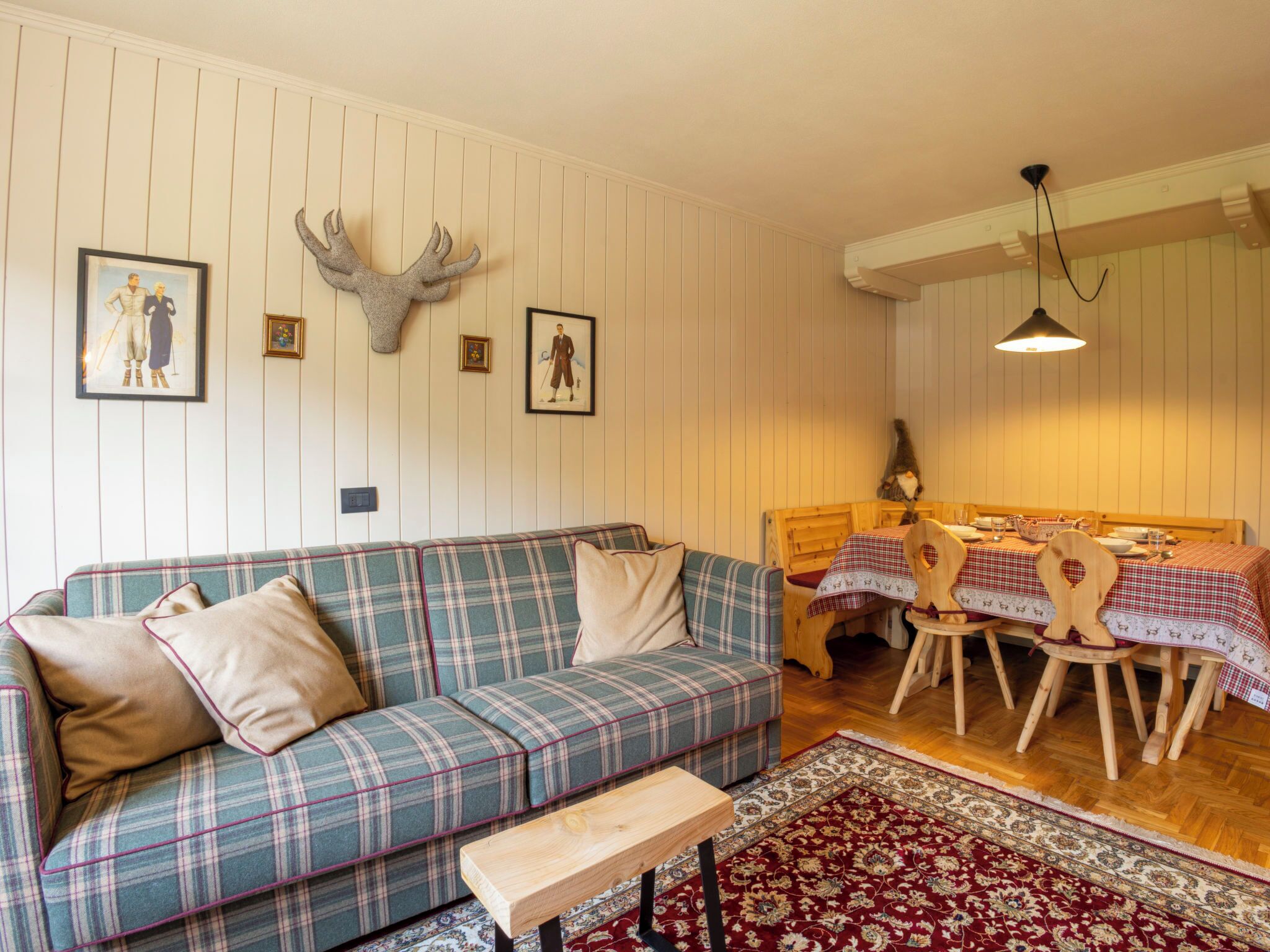 A cozy living room with a plaid sofa, a wooden coffee table, and a dining area with a wooden table and chairs.