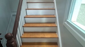 A staircase with wooden steps and white railings, leading to an upper floor.