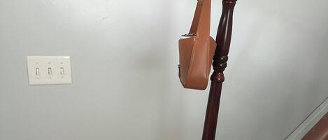 Un perchero de madera con un bolso colgando, un enchufe y un adorno de mapa circular.