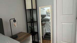 A bedroom with a bed, a bedside table, a mirror, and a wardrobe.