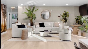 A modern living room with a sofa set, a coffee table, and a round mirror on the wall.