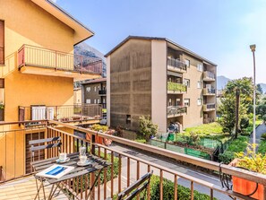 Un immeuble résidentiel doté de balcons, d’un espace extérieur aménagé et couvert, et offrant une vue sur une montagne.