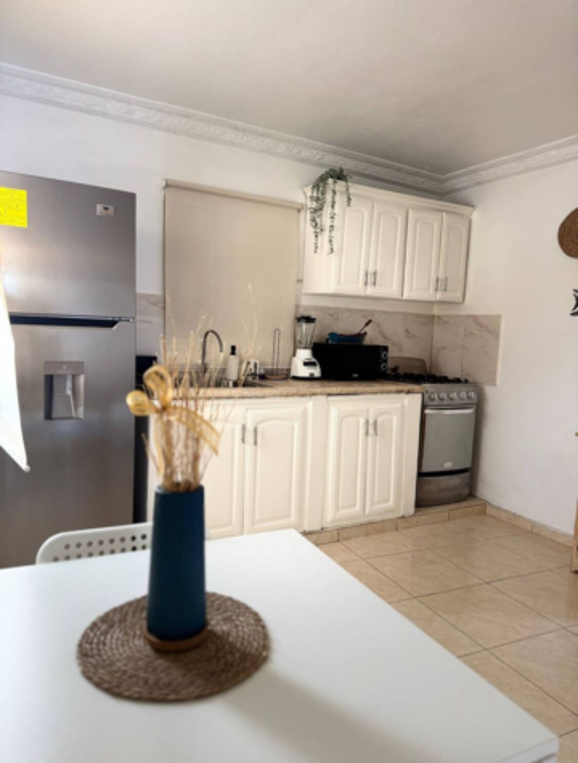 A kitchen with white cabinets, a stainless steel refrigerator, a stove, and a sink.