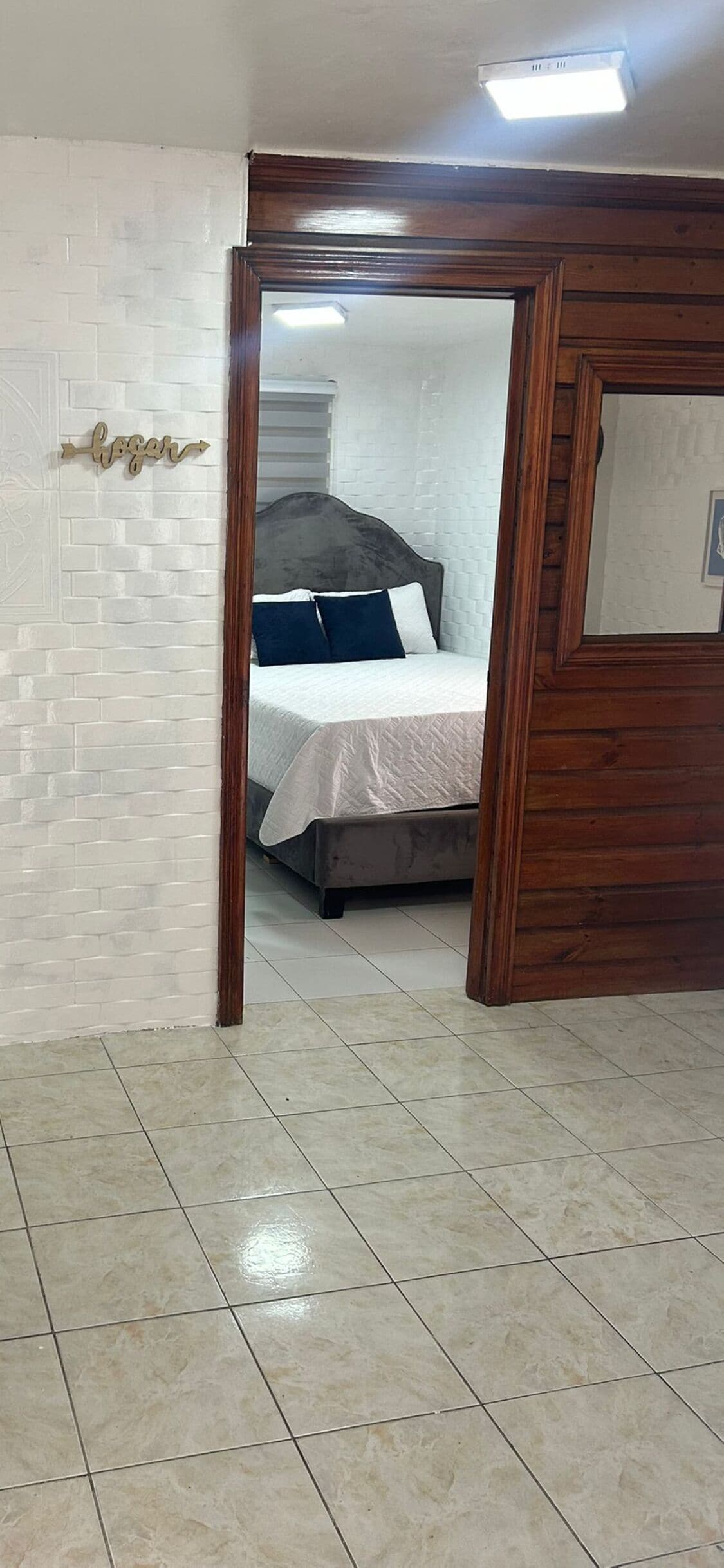 A bedroom with a bed, a wooden door frame, and a white brick wall.