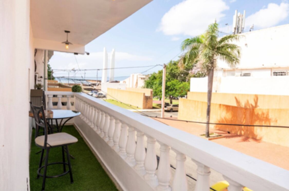 A balcony with a white balustrade, a small table, and two chairs.