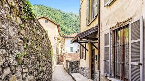 A narrow cobblestone street flanked by historic buildings with stone walls and shutters. - Martino by Interhome (Argegno)