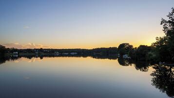 A calm lake with a clear sky, surrounded by trees and houses.