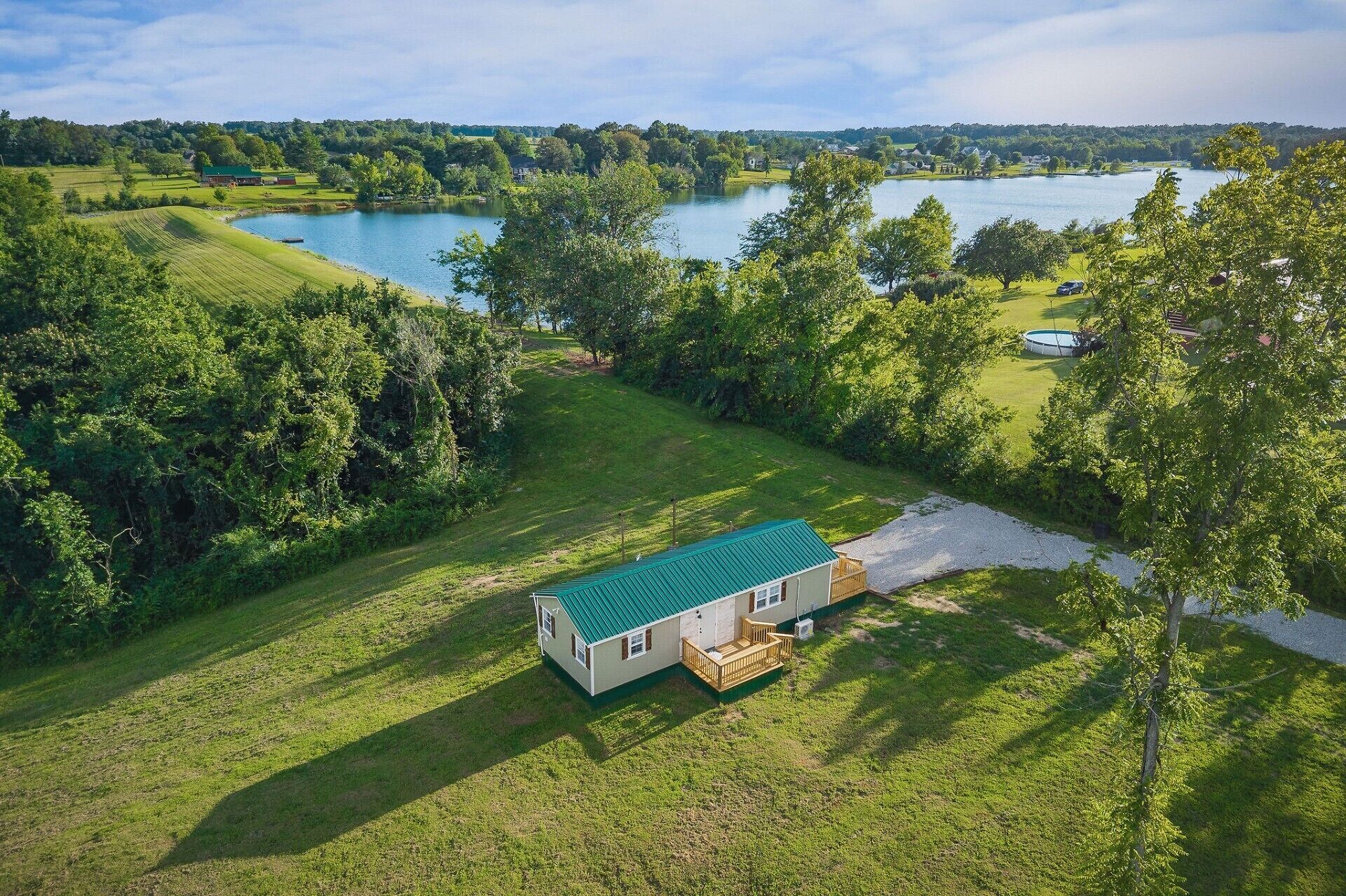 Ein Haus mit einem grünen Dach, umgeben von üppiger Vegetation und einem See.