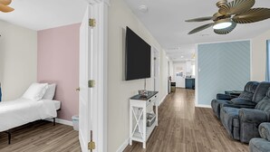 Ein Hotelzimmer mit einem Bett, einer Sitzecke mit einer Couch, einem an der Wand befestigten Fernseher und einem Deckenventilator.