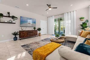 Un salón espacioso con un televisor grande, un mueble de madera, un sofá y una mesa de centro.