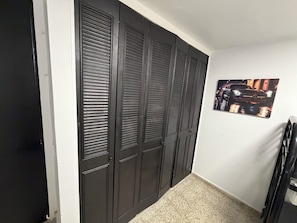 A hallway with a closed door, a wall-mounted picture, and a tiled floor.