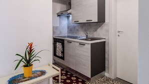 Une cuisine de taille réduite, équipée d’une cuisinière, d’un four et de meubles de rangement modernes.