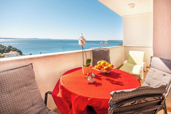 A balcony with a red table, chairs, and a view of the sea. - A 4  apt w terrace & sea view, 4 min walk to beach (Podstrana)