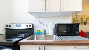 A compact kitchen with a stove, microwave, and a sink.