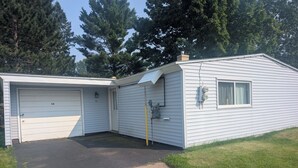 A single-story, white mobile home with two attached garages, a small window, and a chimney. - Near the park! 3-bedroom house with wifi and AC (White Pine)