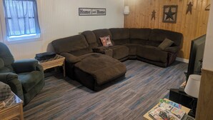 A living room with a sectional sofa, a small table, a lamp, and a television. - Near the park! 3-bedroom house with wifi and AC (White Pine)