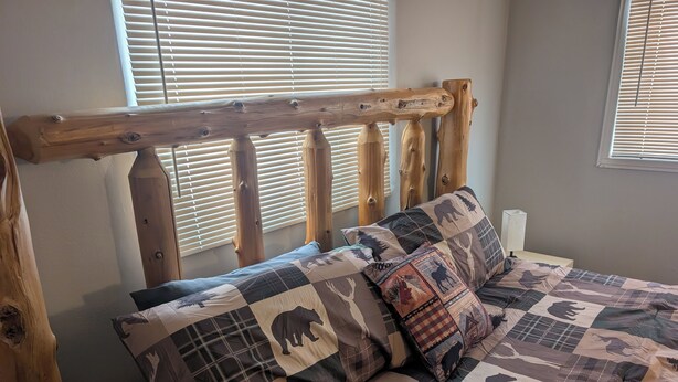 A bed with a quilt featuring animal prints, a wooden headboard, and a window with blinds. - Near the park! 3-bedroom house with wifi and AC (White Pine)