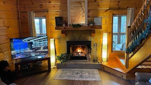 A cozy cabin interior with a fireplace, wooden walls, a television, and a staircase. -  Washer dryer arcade game hot tub Waterview 3 bedroom 4 bed Awesome cabin.  (Sevierville)