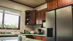 A kitchen with a marble countertop, stainless steel appliances, wooden cabinets, and a window providing natural light.