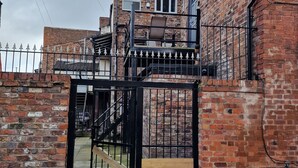 A brick building with a gated entrance, a staircase, and a small balcony.