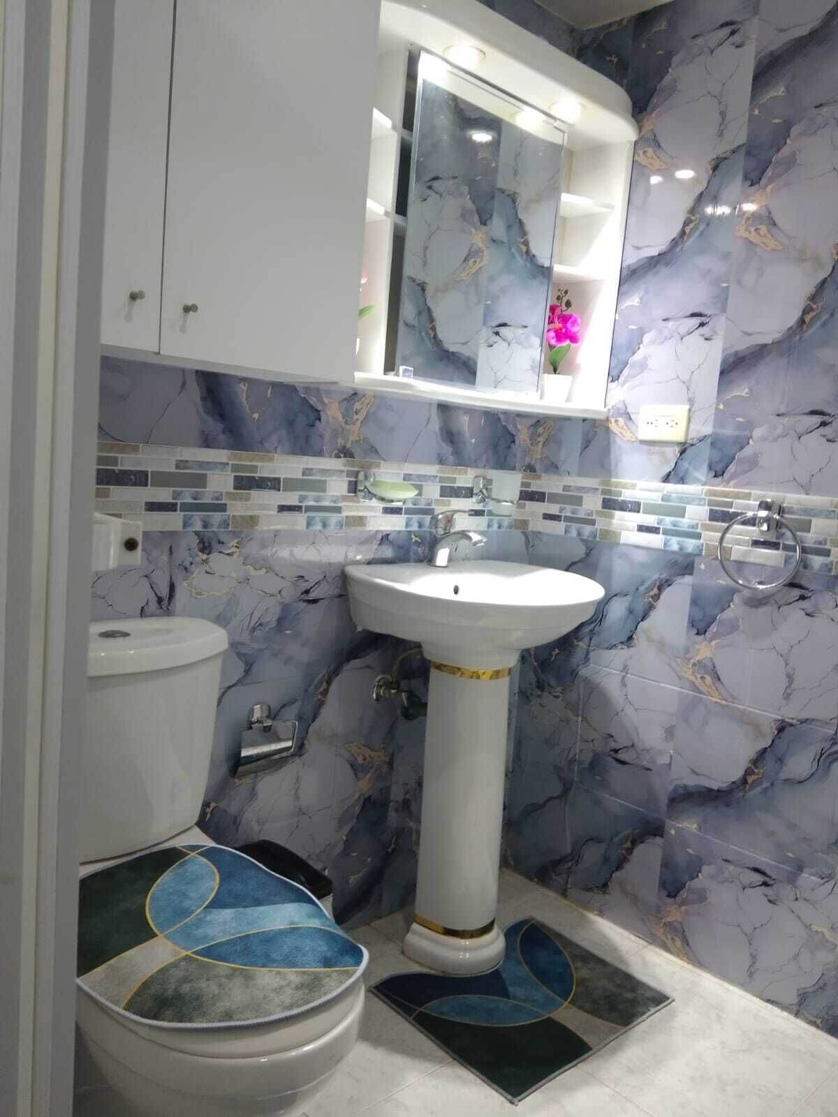 Un bagno con un lavandino bianco su piedistallo, un water e uno specchio sopra il lavandino.