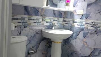 Un bagno con un lavandino bianco su piedistallo, un water e uno specchio sopra il lavandino.