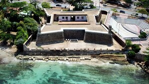 Luchtbeeld van een kustfort met een centrale binnenplaats, omgeven door een stenen muur en een strand.