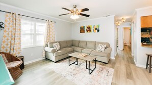 A modern living room with a sectional sofa, a coffee table, and a ceiling fan.