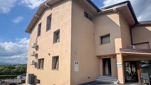 A two-story building with a beige facade, multiple windows, and a parking area in front. - Adelsberg Inn by Interhome (Postojna)
