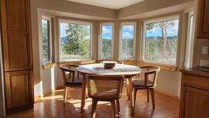 A dining area with a round table and six chairs, large windows with a view of trees and mountains, wooden cabinets, and a ceiling light. - The Outlook-Golden Gate Canyon, Black Hawk
3BR/2BA mountain home sleeps 6 guests (Black Hawk)