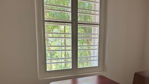 A room with a single window, a wooden table, and a chair.