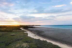 A coastal landscape with a beach, grassy areas, and a river.