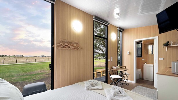 Una habitación de hotel moderna con una cama grande, un escritorio, una silla y un televisor.