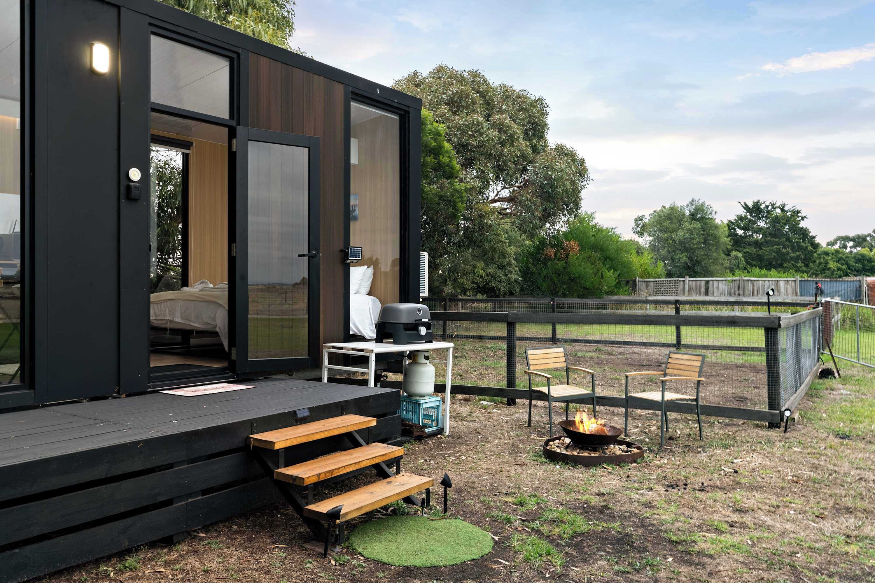 A modern outdoor deck with a grill, seating, and a fire pit.