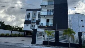 Un immeuble moderne à plusieurs étages, doté de balcons, d’une entrée sécurisée et d’un espace de stationnement.