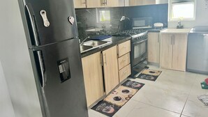 Une cuisine moderne équipée d’un réfrigérateur en acier inoxydable, de meubles de rangement en bois, d’une cuisinière à gaz et d’un four à micro-ondes.