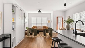 A modern kitchen with a central island, wooden flooring, and a dining area with a sofa. - CP ~ Hot Tub ~ Outdoor Lounge & TV ~ Walkable to Local Food & Drinks ~ Free Parking ~ Sleeps 10 (Nashville)