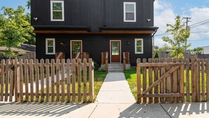 A two-story house with a dark exterior, a front door, and a small porch. - CP ~ Hot Tub ~ Outdoor Lounge & TV ~ Walkable to Local Food & Drinks ~ Free Parking ~ Sleeps 10 (Nashville)