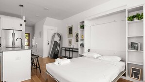 A modern bedroom with a large bed, a built-in wardrobe, and a kitchen area with a refrigerator and sink. - CP ~ Hot Tub ~ Outdoor Lounge & TV ~ Walkable to Local Food & Drinks ~ Free Parking ~ Sleeps 10 (Nashville)