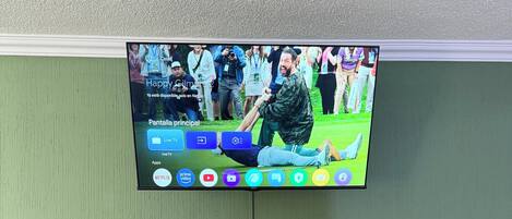 Un televisor montado en la pared con un mueble de madera debajo.
