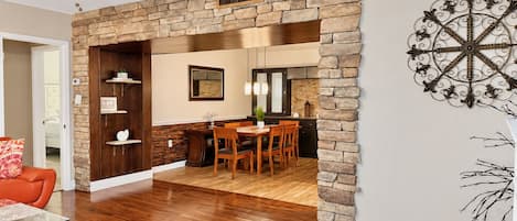 A dining area with a stone wall, wooden furniture, and a ceiling fan.