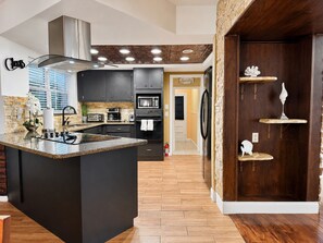 A modern kitchen with a central island, built-in appliances, and a stone accent wall.