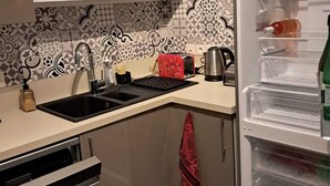 A kitchen with a built-in dishwasher, a sink, a refrigerator with a clear door, and a patterned backsplash. - Large apartment with private garden (Arcachon)